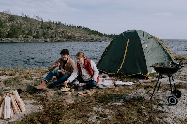 5 Reasons Why You Need A Water Tank For Your Next Adventure 1 couple sitting on picnic mat near a tent along a river